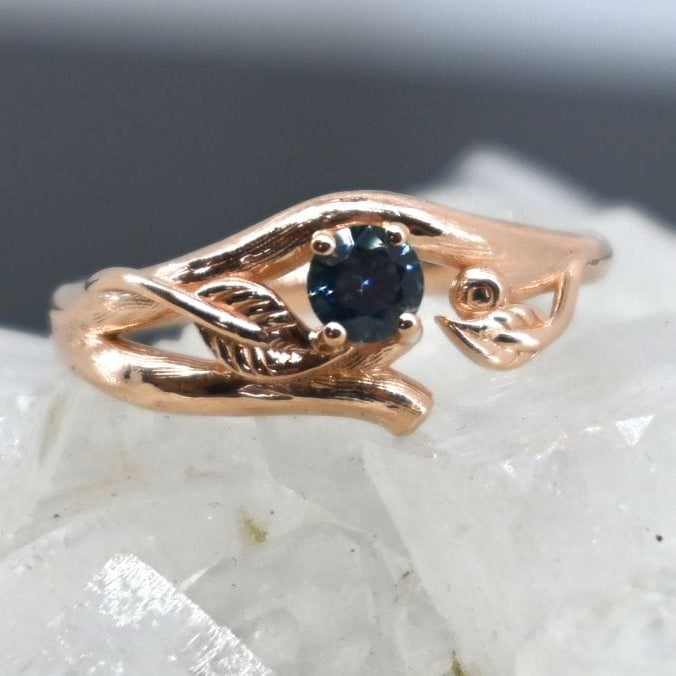 Rose gold ring with a blue sapphire on a white stone background
