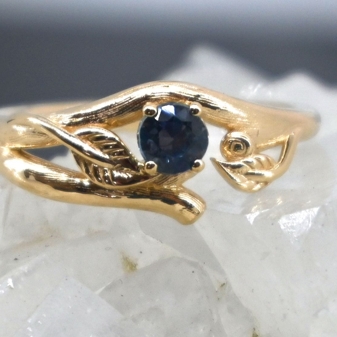 Gold ring with a blue sapphire on a textured surface