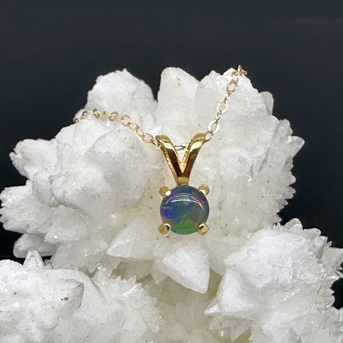 Gold necklace with an opal pendant on a white crystal background