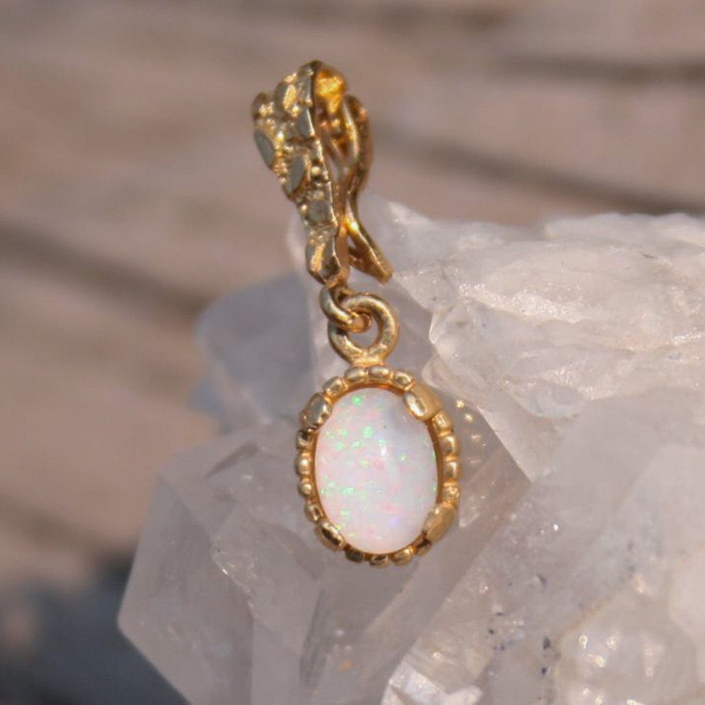 Gold pendant with an opal stone hung on a nugget textured bail