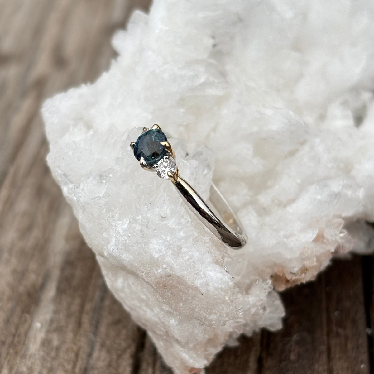 Side profile engagement ring with large teal sapphire and diamonds. 