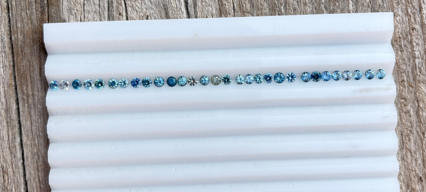Row of blue Montana sapphires on a white tray.