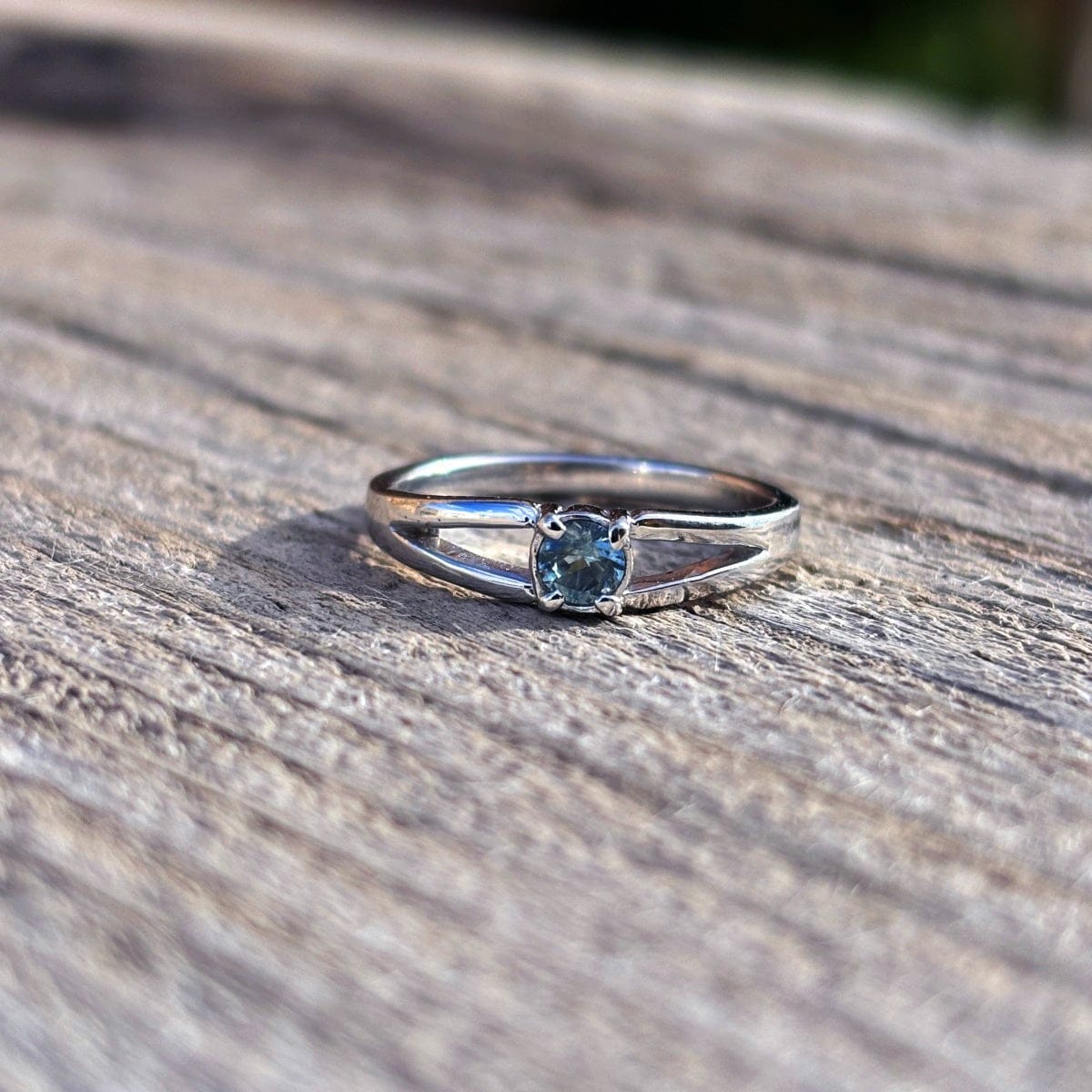 Silver ring with a round blue sapphire in a split shank band. 