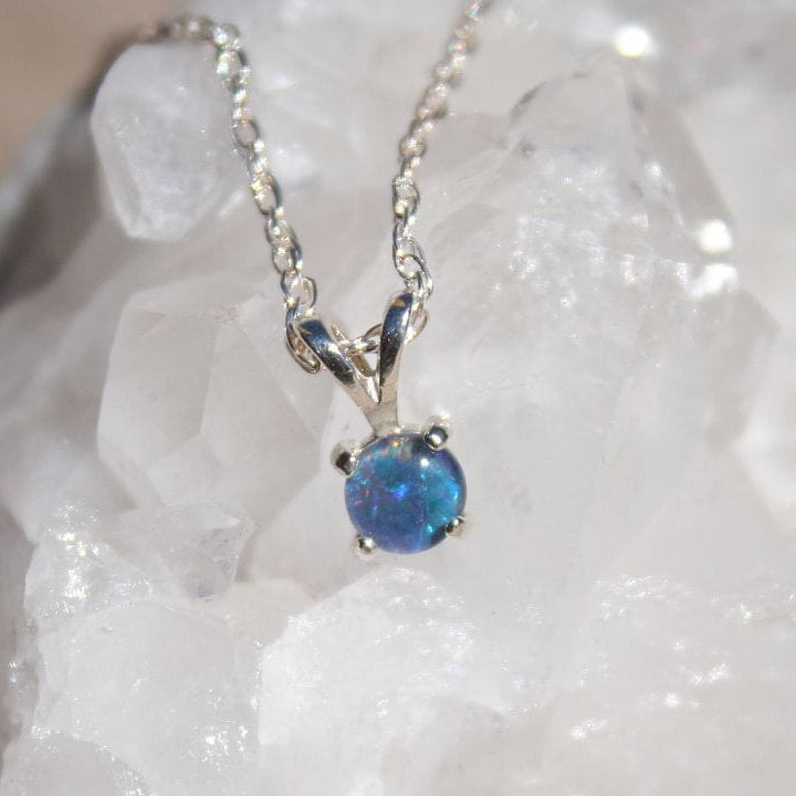 Blue opal pendant necklace on a white stone background