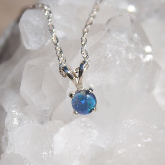 Blue opal pendant necklace on a white stone background