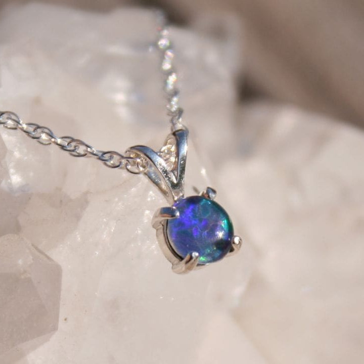 Opal pendant necklace on a chain with a white stone background