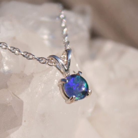 Opal pendant necklace on a chain with a white stone background