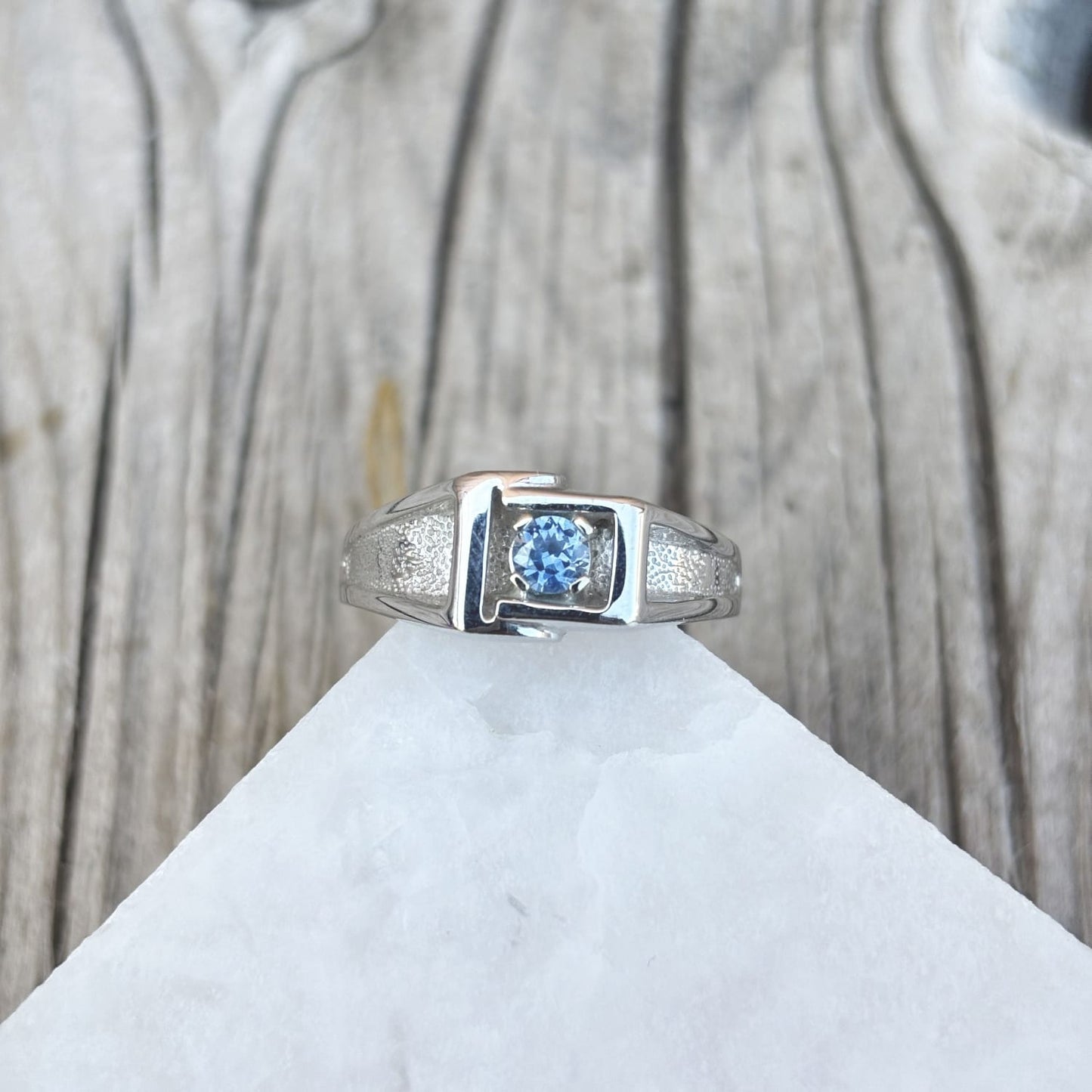Gents ring with an abstract design framing a 4mm medium blue Montana sapphire in 14k white gold 