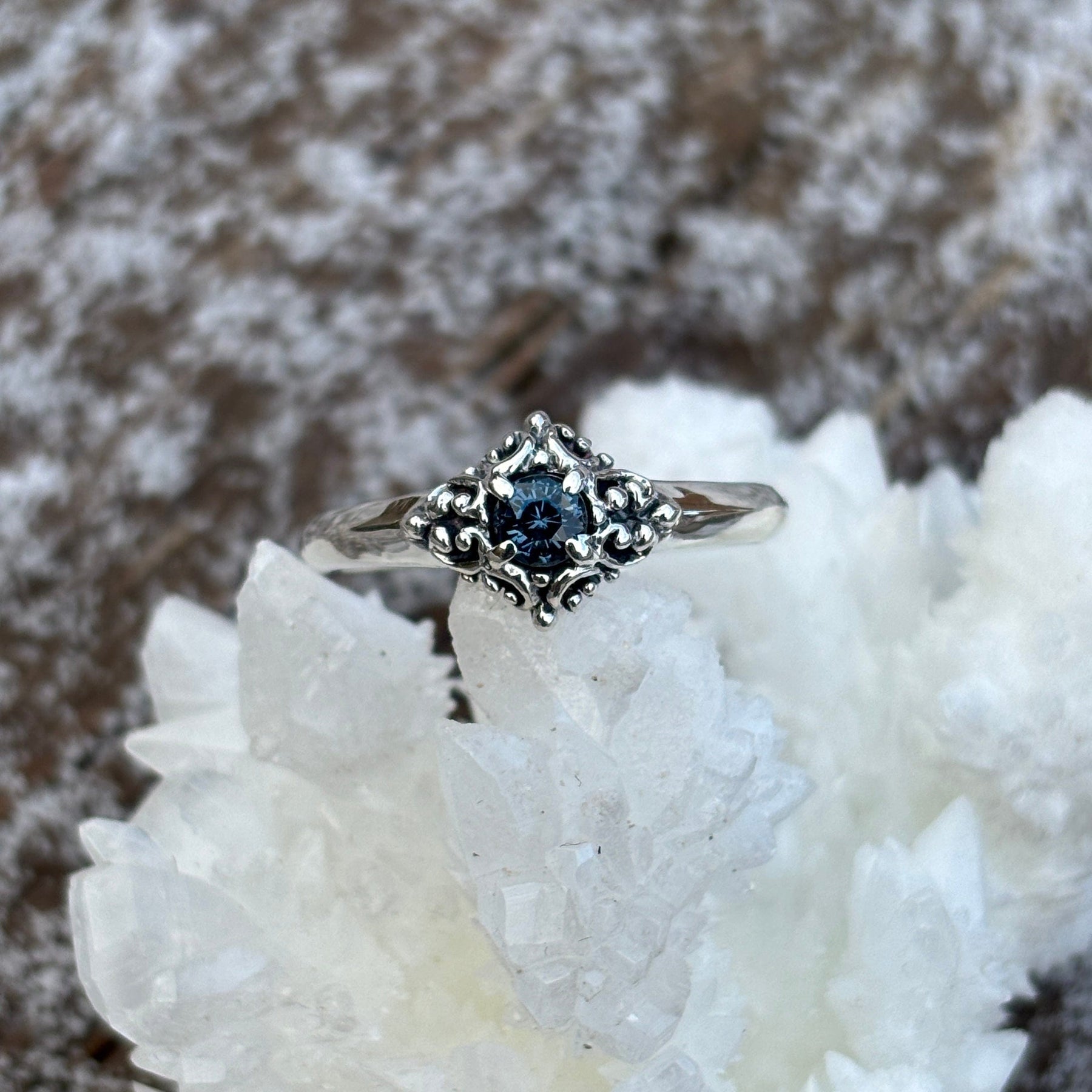 Silver ring with blue Montana sapphire and filigree halo in a diamond shape. 