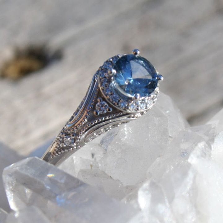 White gold ring with a large blue Montana sapphire with diamond halo in vintage style setting