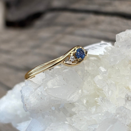 Yellow gold ring with dainty round yogo blue sapphire center and 2 small diamonds
