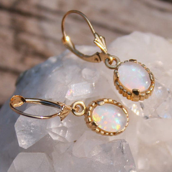Gold earrings with opal stones on a crystal background