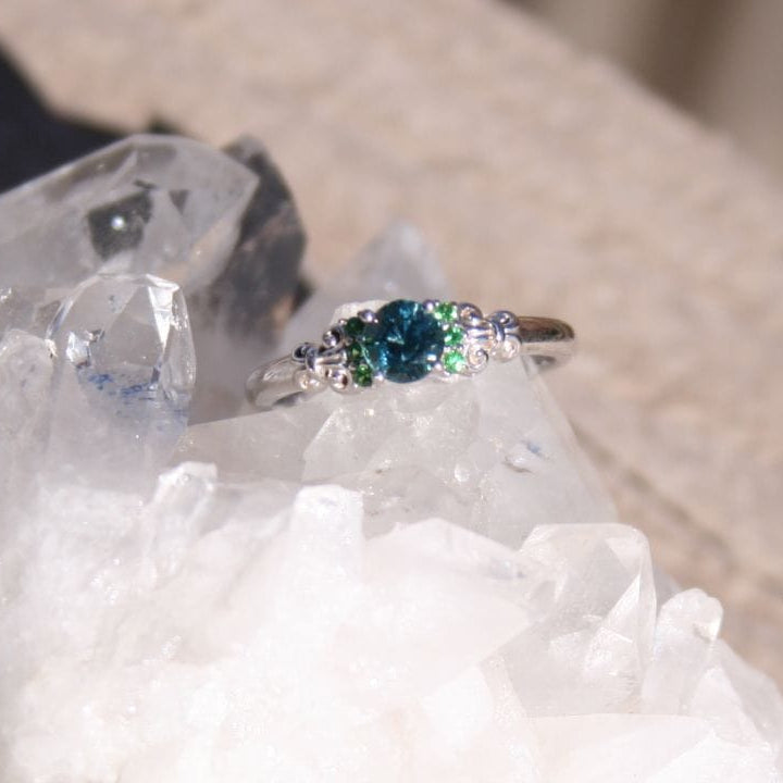 Engagement ring with blue Montana sapphire and green garnets on quartz crystals