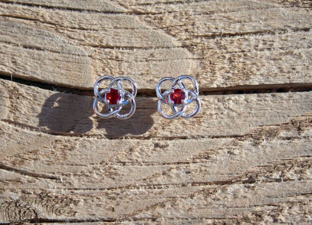 Red gem earrings on wood grain