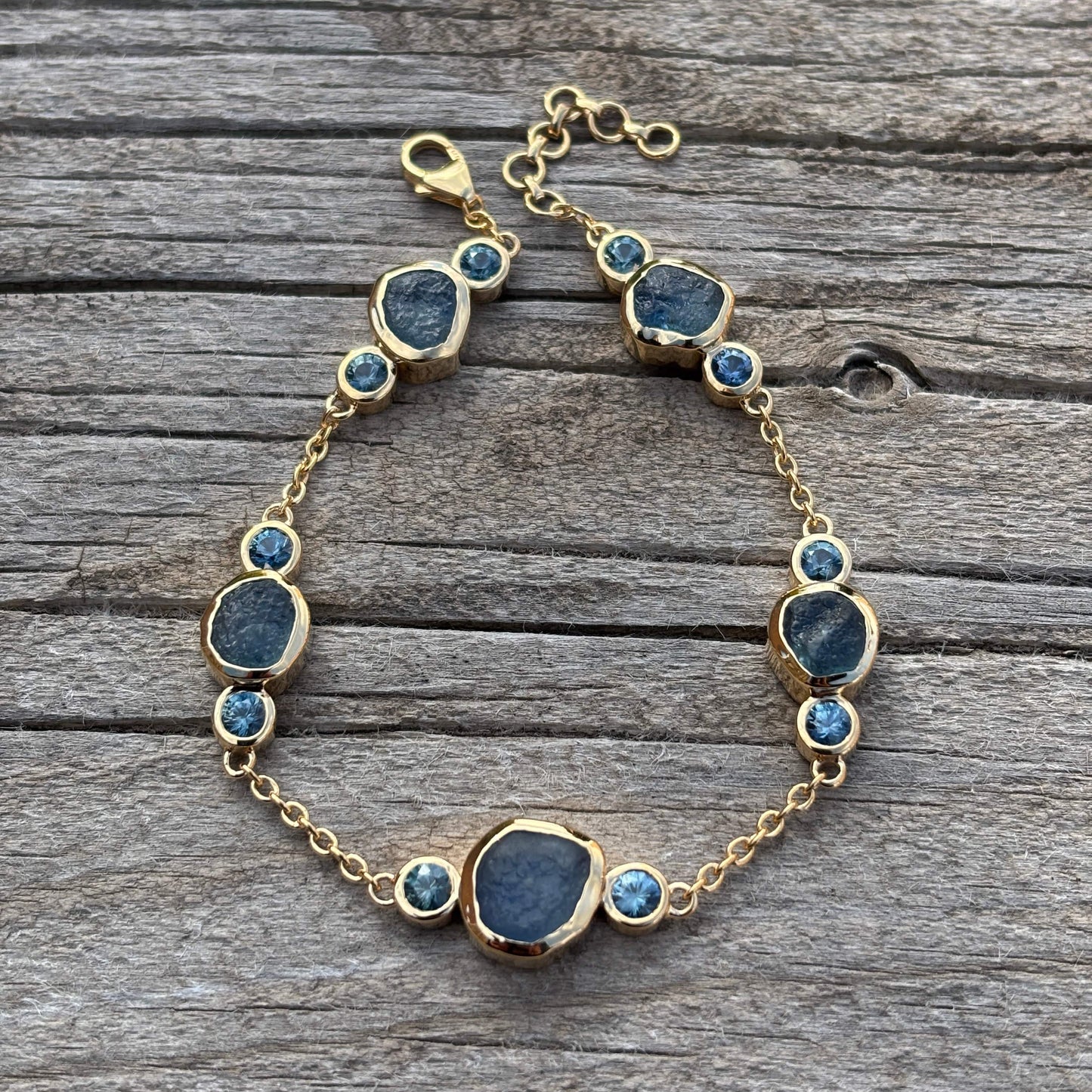 Bracelet with blue cut and uncut sapphires on a wooden surface