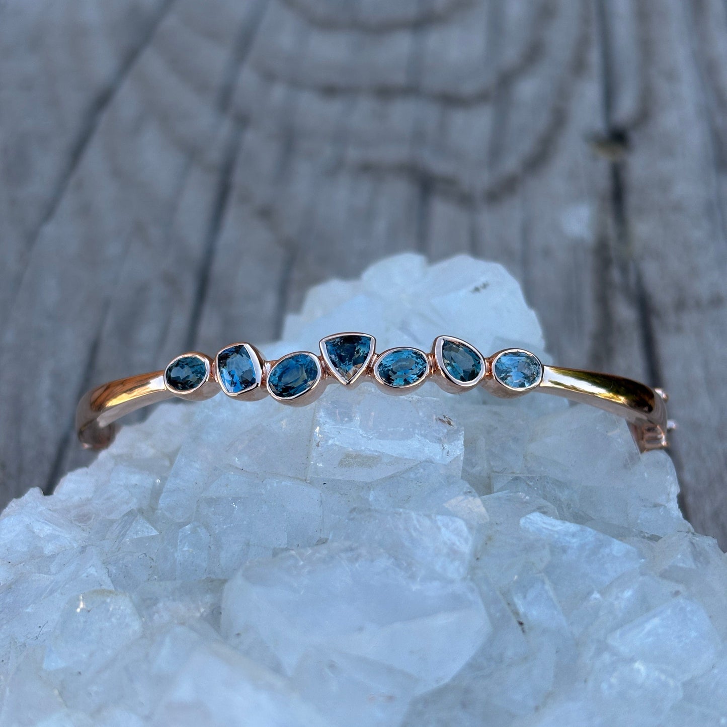 Rich blues multi-shaped sapphires in a rose gold hinged cuff