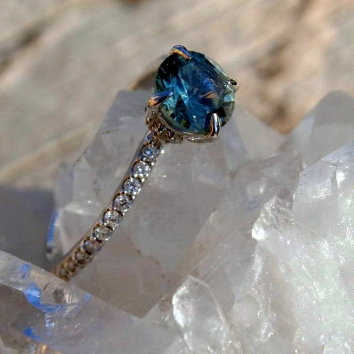 Teal Montana Sapphire in a gold and diamond accented band with a hidden diamond halo. 