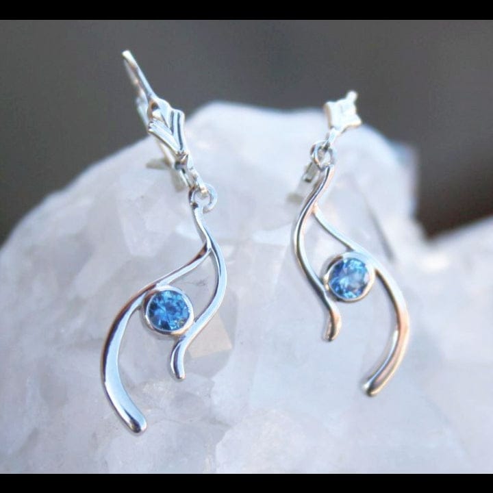 Silver earrings with blue Montana sapphires on a white stone surface
