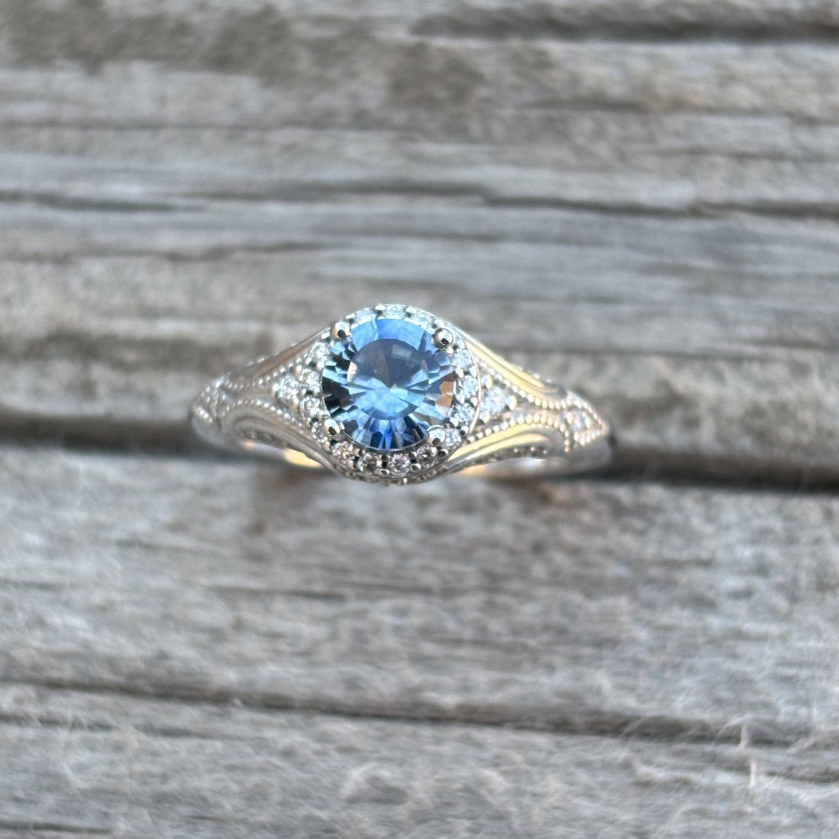 Antique style diamond halo ring with a large blue Montana Sapphire