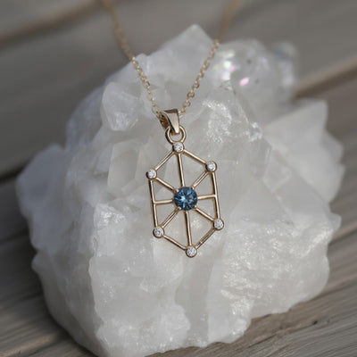 14k yellow gold art-deco inspired pendant with a Montana sapphire as the center and 6 small natural diamond accents
