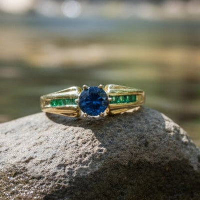Gold ring with blue Montana sapphire and green emeralds in yellow gold
