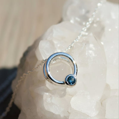 Silver ring with a blue gemstone on a white stone background