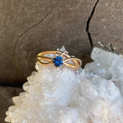 gold criss-cross style ring with blue Montana sapphire