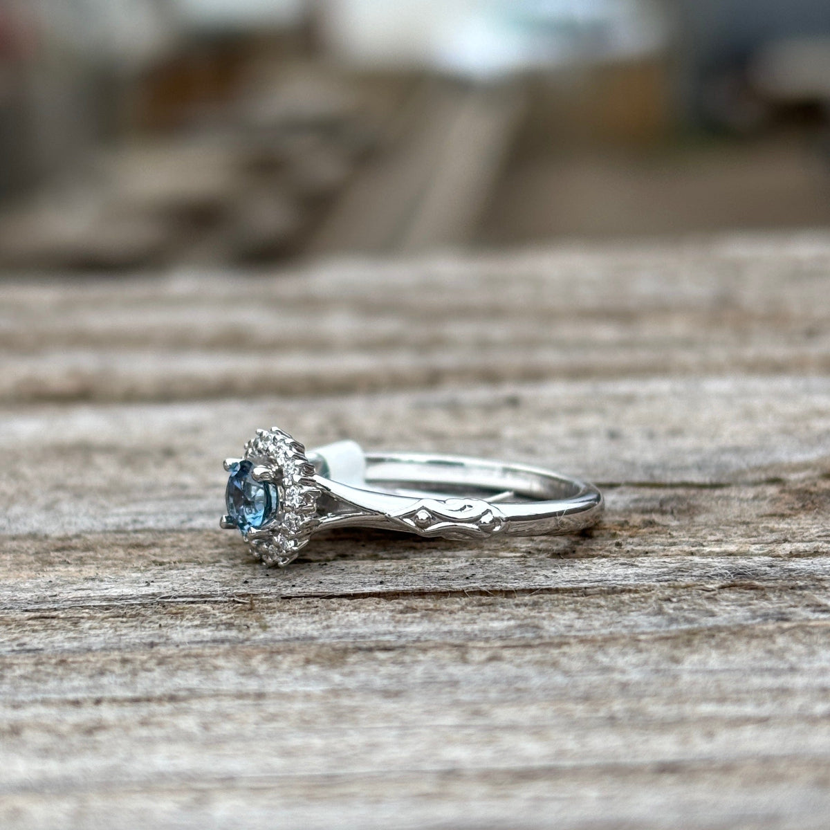 Side view white gold engagement ring  with a teal Montana sapphire with diamond halo 