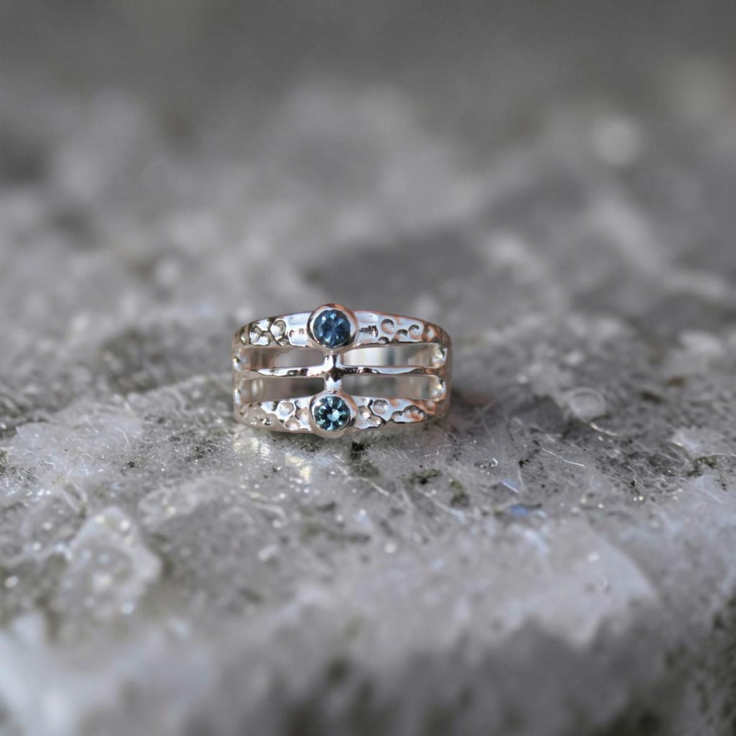A wide band hammered finish ring featuring two Montans sapphires in different colors.  Geometric and modern looking. 