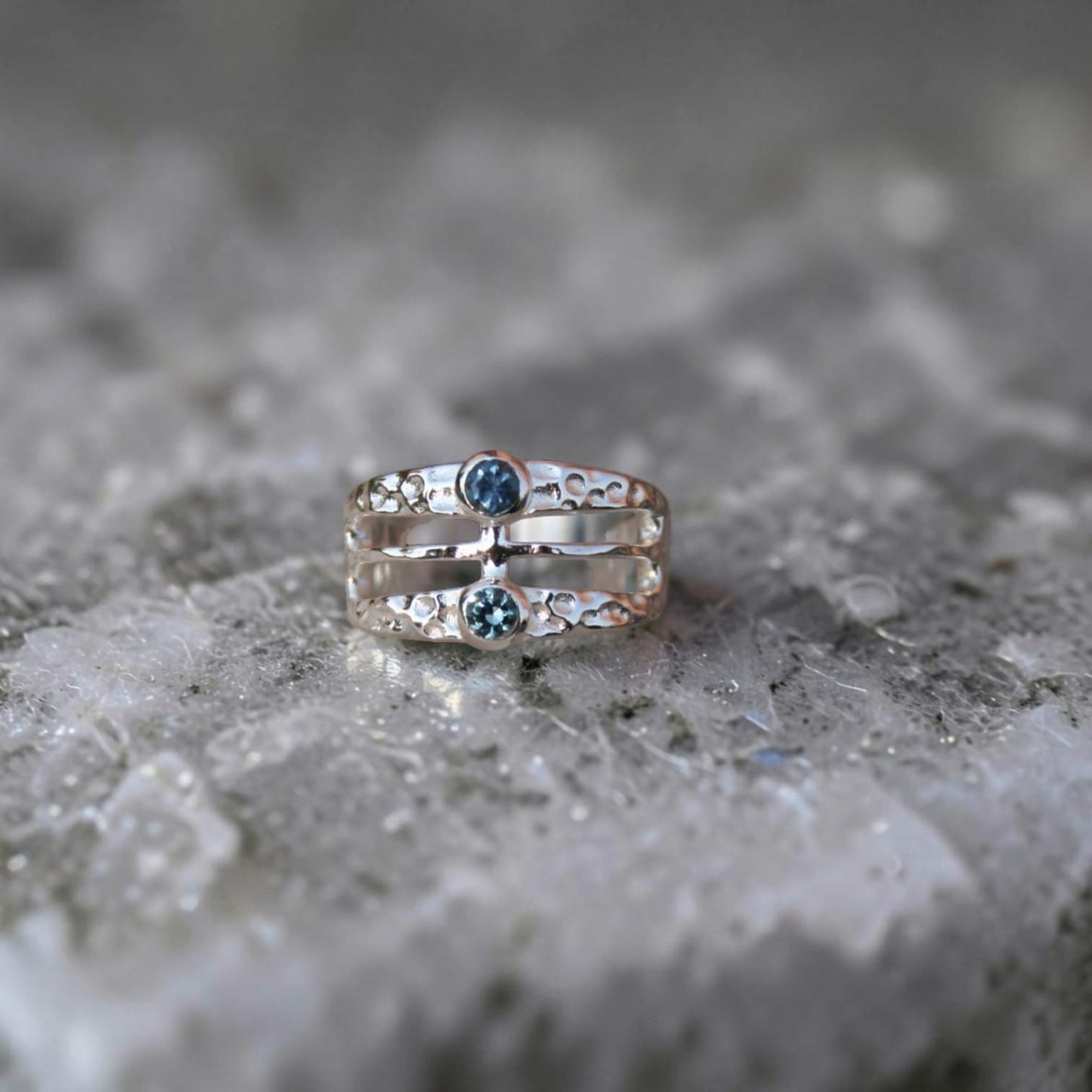 A wide band hammered finish ring featuring two Montans sapphires in different colors.  Geometric and modern looking. 