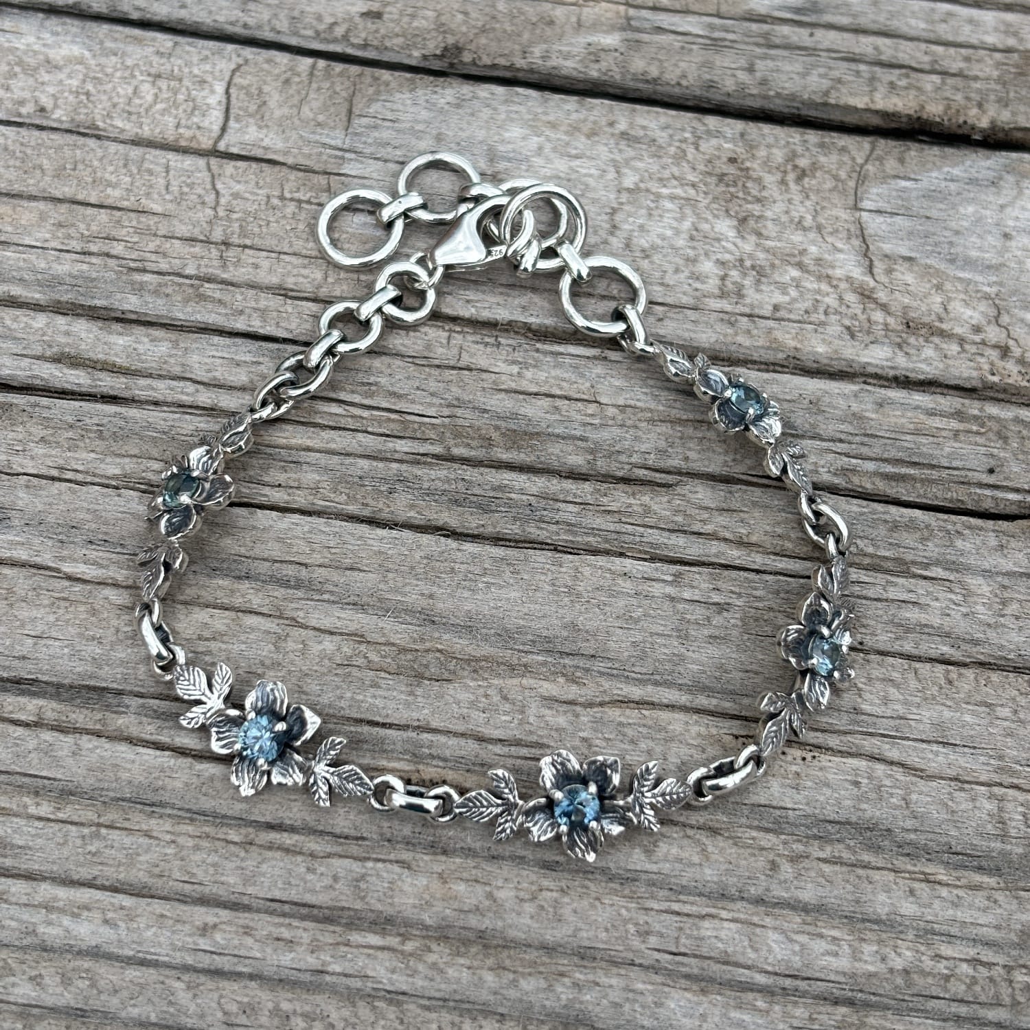A sterling silver chain bracelet with small floral motifs and blue Montana sapphires for the  centers.