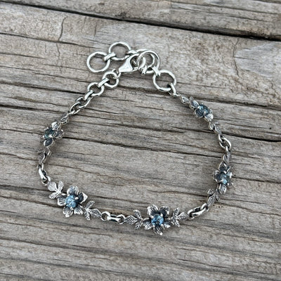 A sterling silver chain bracelet with small floral motifs and blue Montana sapphires for the  centers.