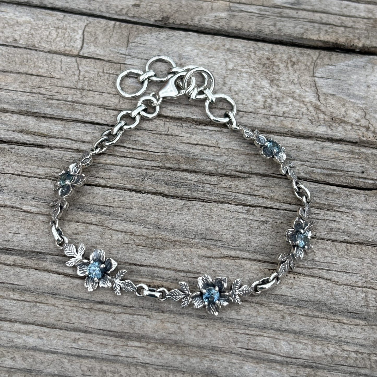 A sterling silver chain bracelet with small floral motifs and blue Montana sapphires for the  centers.
