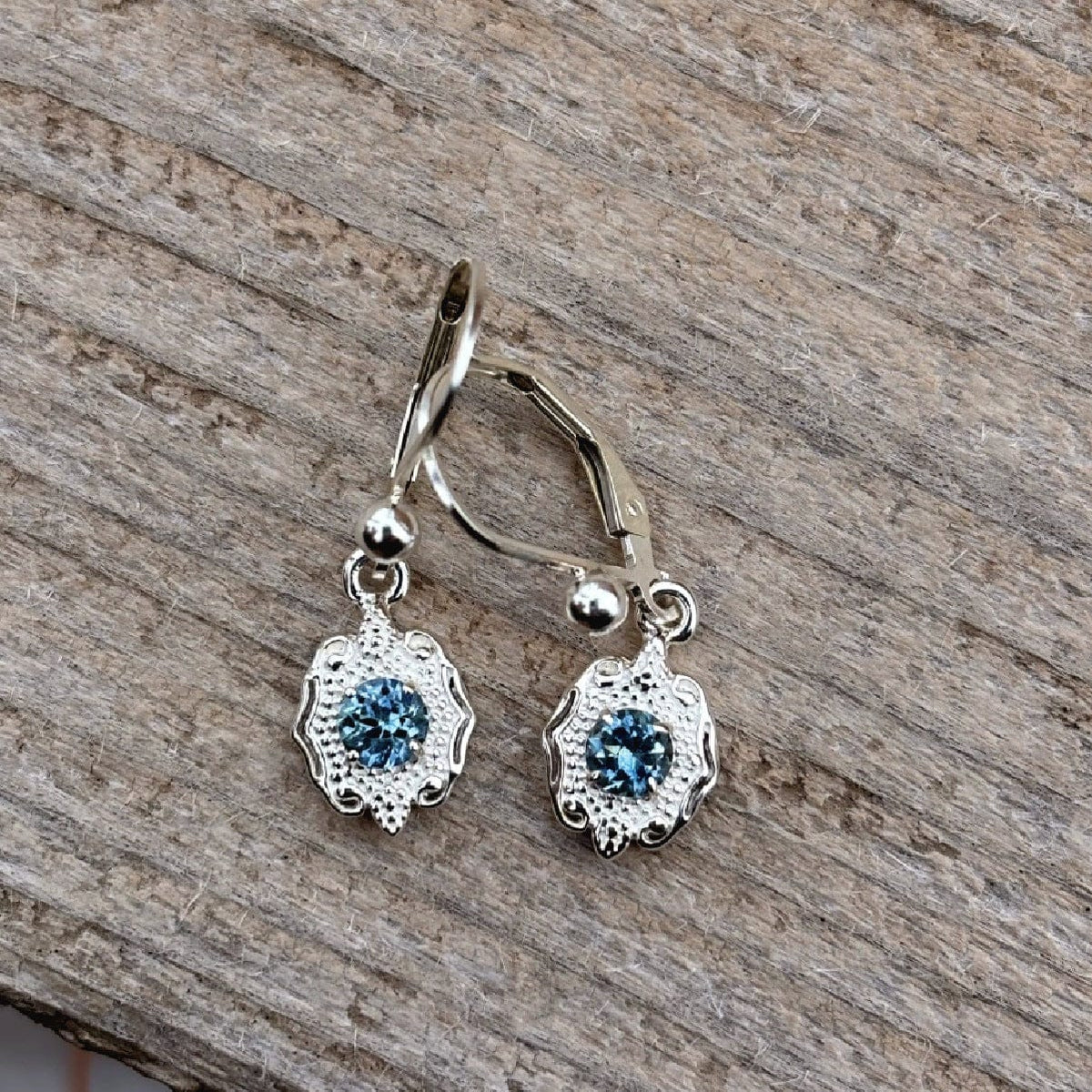 Silver earrings with blue Rock Creek Montana sapphires on a wooden surface