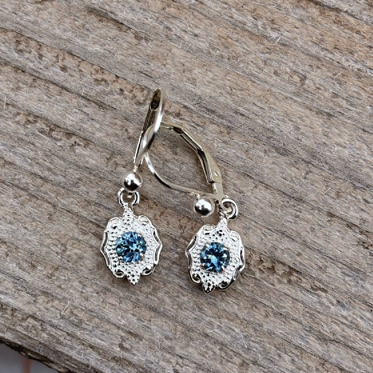 Silver earrings with blue Rock Creek Montana sapphires on a wooden surface