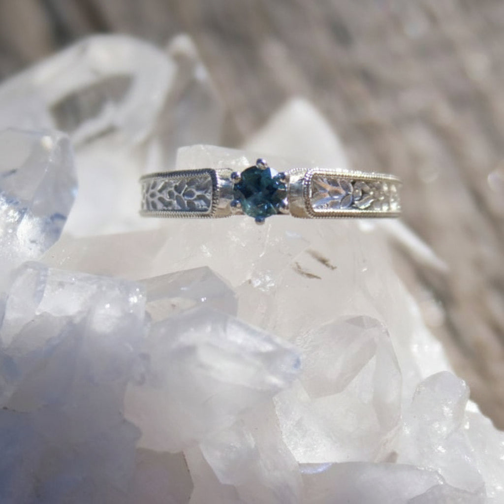 Silver ring with a blue Montana sapphire gemstone on a crystal surface