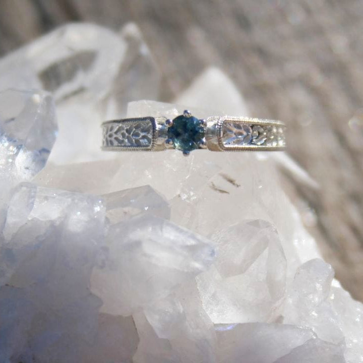 Silver ring with a blue Montana sapphire gemstone on a crystal surface
