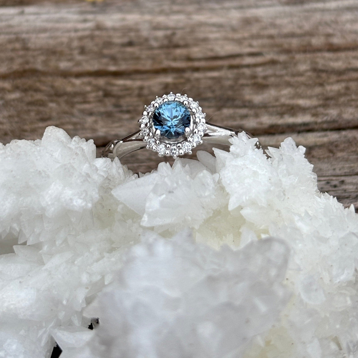 White gold engagement ring with diamond halo and blue Montana sapphire center.  Textured band. 
