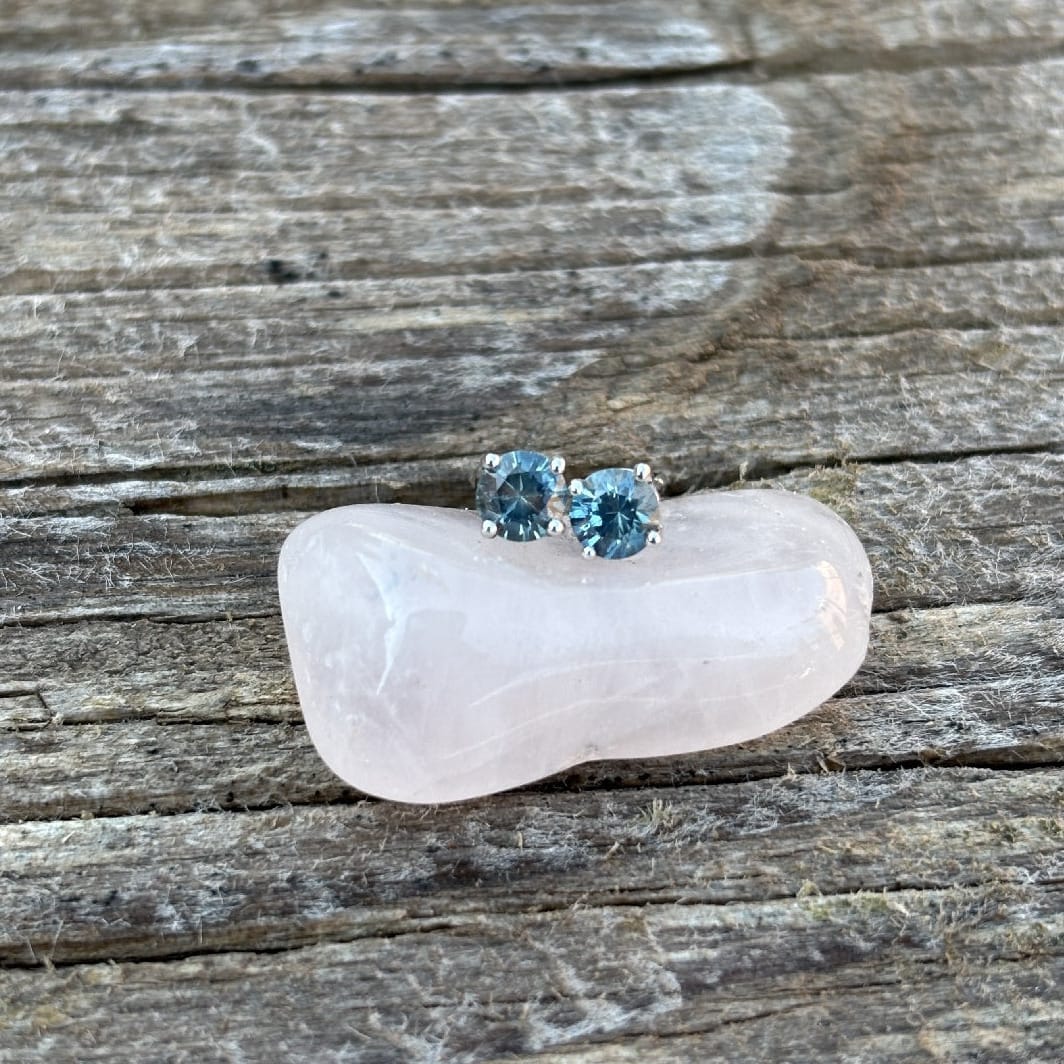 A pair of stud earrings with round blue Montana sapphires in a silver setting.