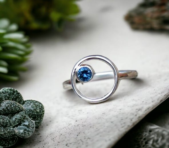 Blue sapphire ring in an open circle negative space bezel set design.