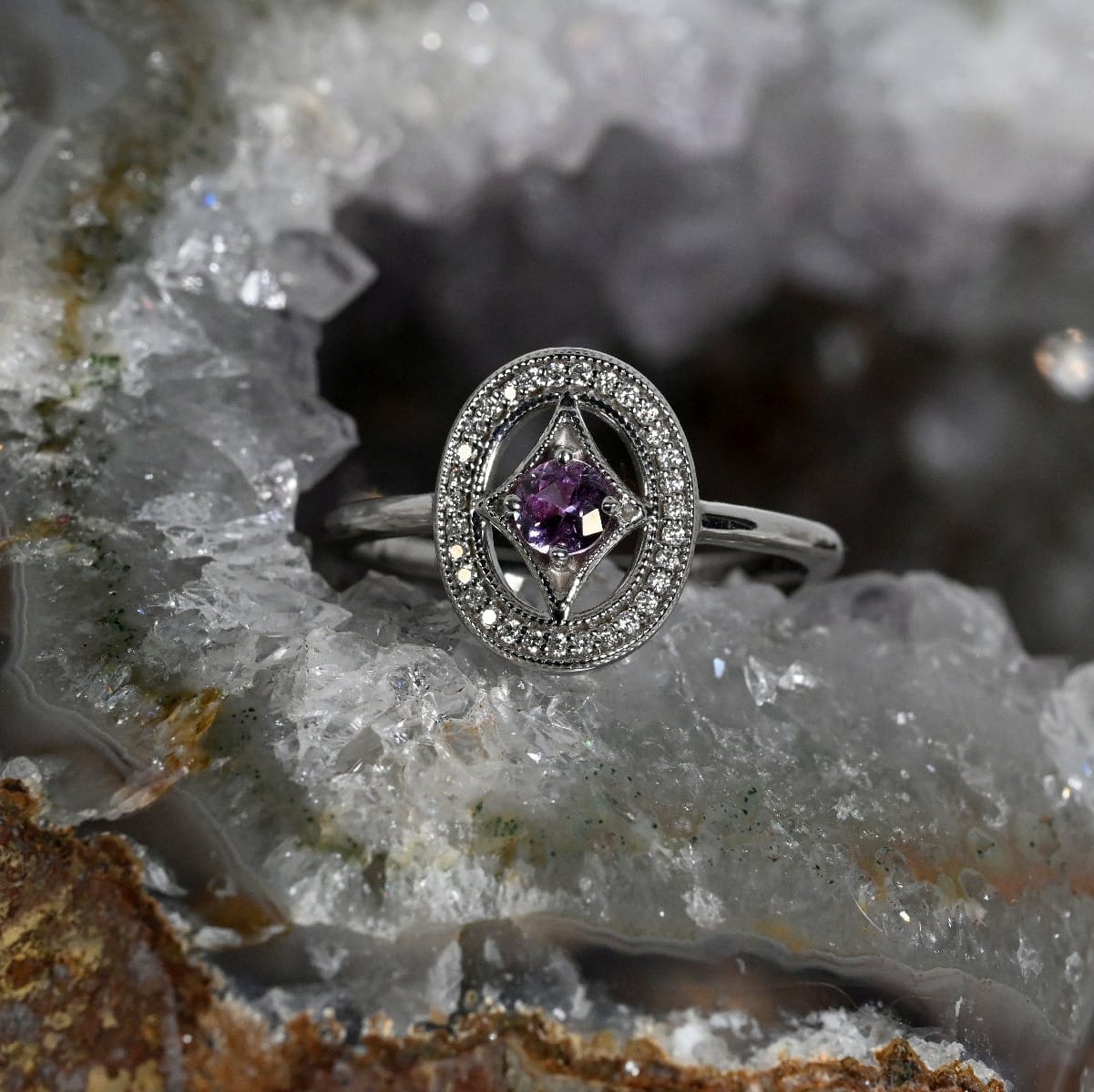 An oval shield style ring with a pink Montana sapphire as the center.  This sapphire is surrounded by pavé-set diamonds. 