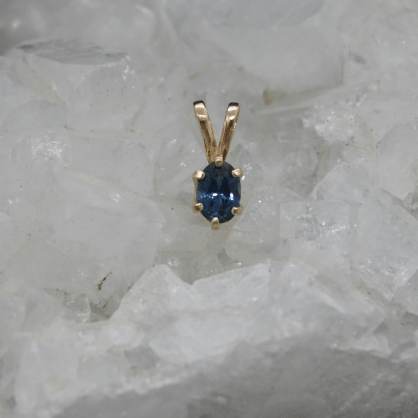 Gold pendant with a blue gemstone on a crystal background