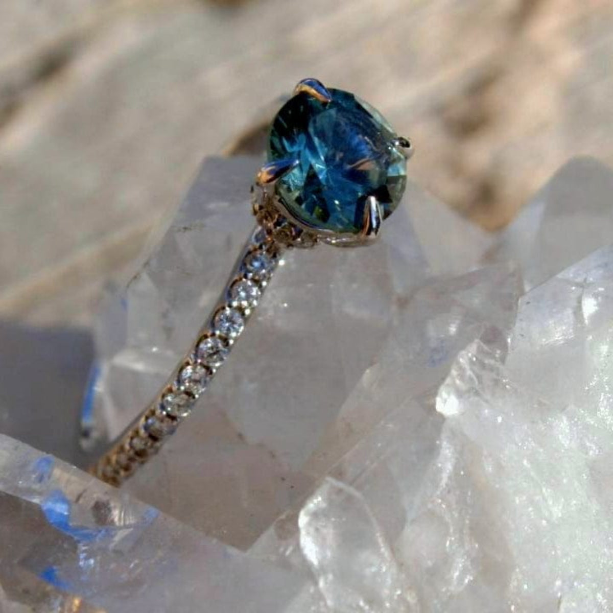 Teal Montana Sapphire in a gold and diamond accented band with a hidden diamond halo. 