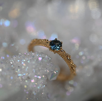 Twisted and beaded band in 14k Yellow gold holding a bright, medium blue Montana sapphire.